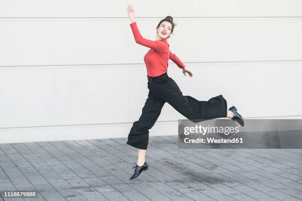 elegant young women jumping in front of a wall - woman trousers stock pictures, royalty-free photos & images