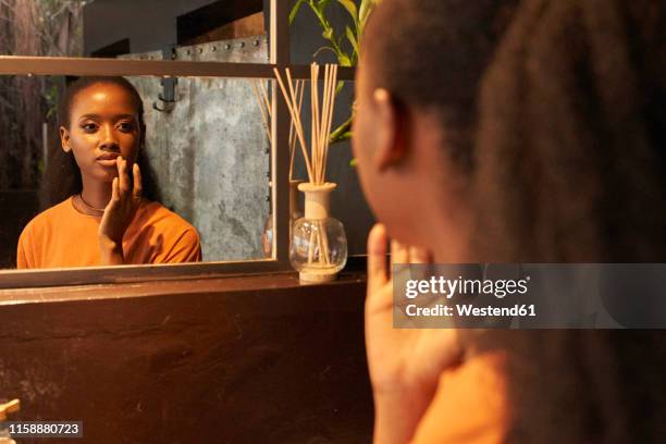 young woman looking in bathroom mirror - self reflection stock pictures, royalty-free photos & images