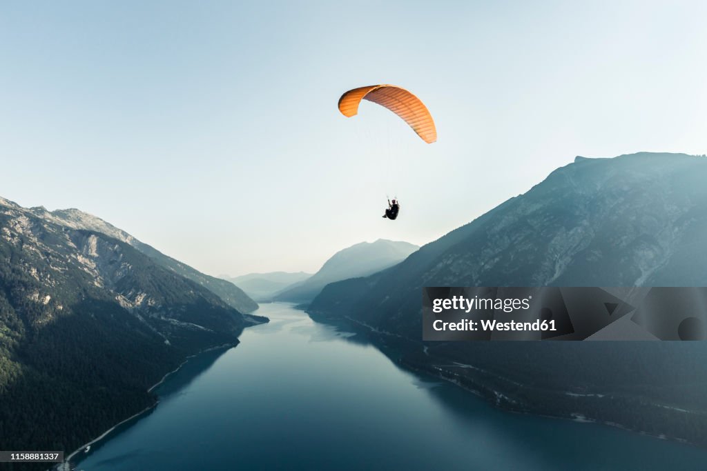 Austria, Tyrol, Paraglider over lake Achensee in the early morning