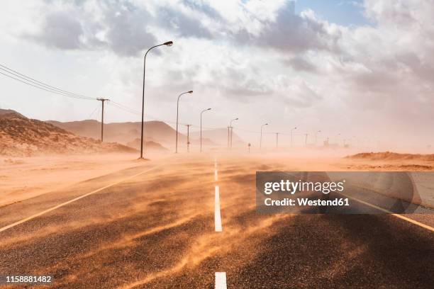sultanate of oman, ras al hadd, desert road in a sand storm - schneewehe stock-fotos und bilder