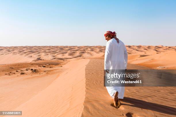 bedouin walking in the desert, wahiba sands, oman - bedouin stock-fotos und bilder