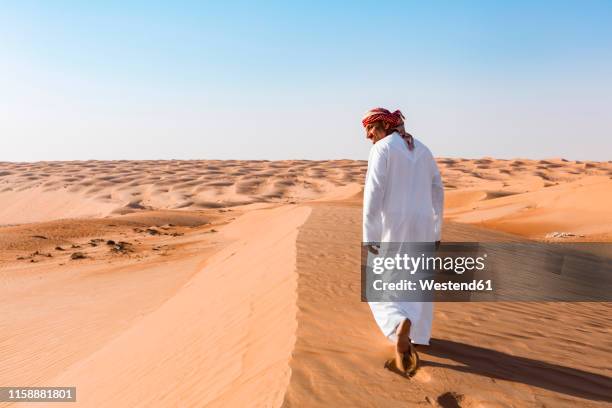 bedouin walking in the desert, wahiba sands, oman - beduino fotografías e imágenes de stock