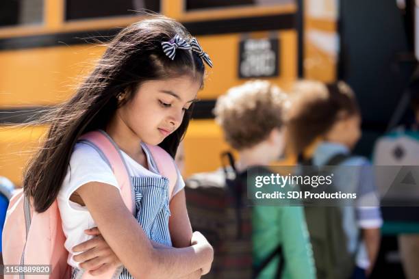 lonely little girl in front of school bus - school exclusion stock pictures, royalty-free photos & images