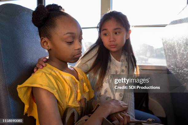 on bus, young girl consoles her sad friend - best friends kids stock pictures, royalty-free photos & images