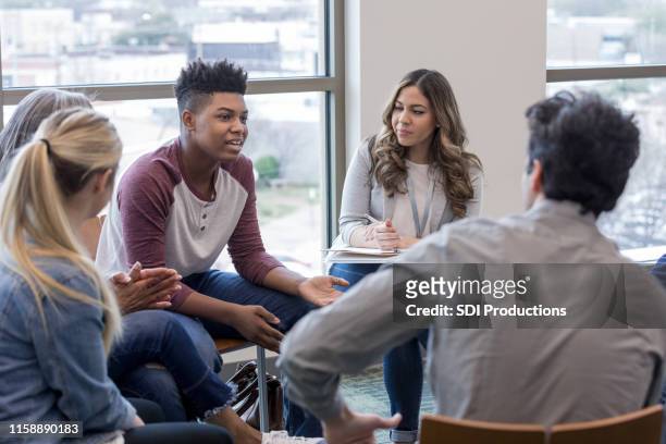 in therapy, teen boy shares life experiences with group - group discussion imagens e fotografias de stock