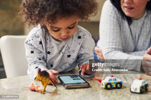 child using a smartphone - toy dinosaur fotografías e imágenes de stock