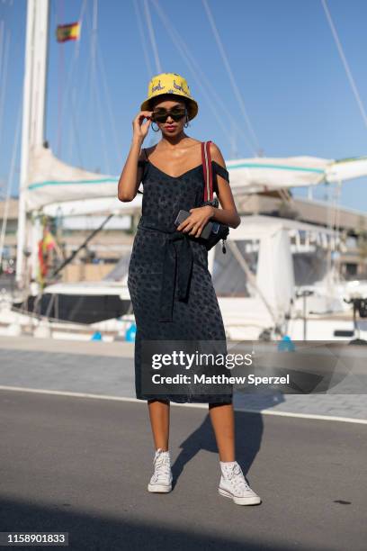 Guest is seen on the street attending 080 Barcelona Fashion Week wearing black dress with yellow bucket hat on June 28, 2019 in Barcelona, Spain.