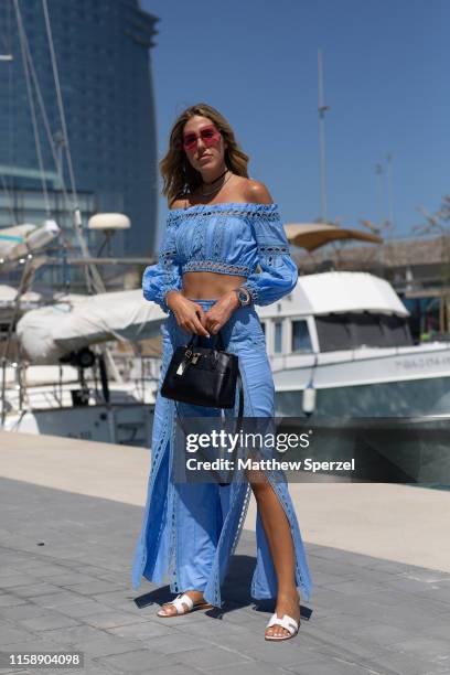 Guest is seen on the street attending 080 Barcelona Fashion Week wearing blue outfit with crop top and skirt, black bag and white sandals on June 28,...