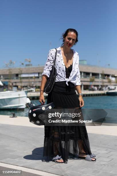 Guest is seen on the street attending 080 Barcelona Fashion Week wearing white/black polka dot shirt and motorcycle helmet, black sheer skirt, black...