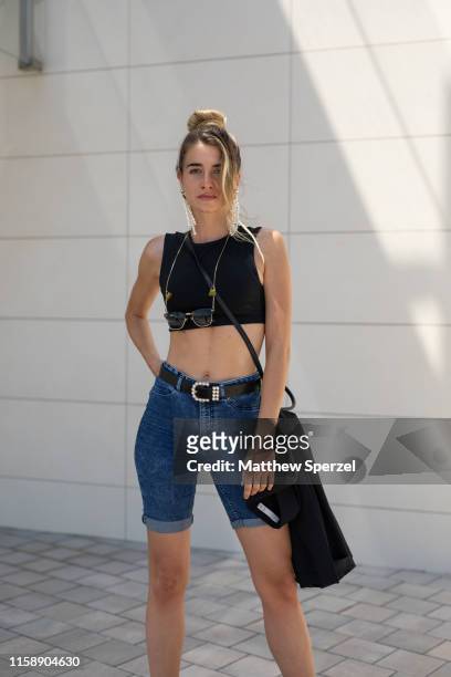 Guest is seen on the street attending 080 Barcelona Fashion Week wearing black crop top, jean shorts, black belt and bag on June 28, 2019 in...