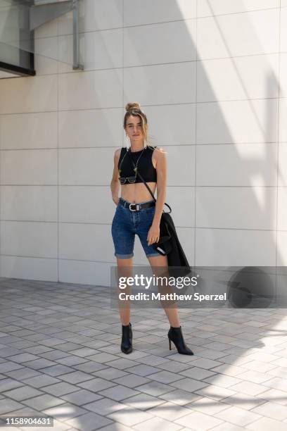 Guest is seen on the street attending 080 Barcelona Fashion Week wearing black crop top, jean shorts, black belt and bag on June 28, 2019 in...