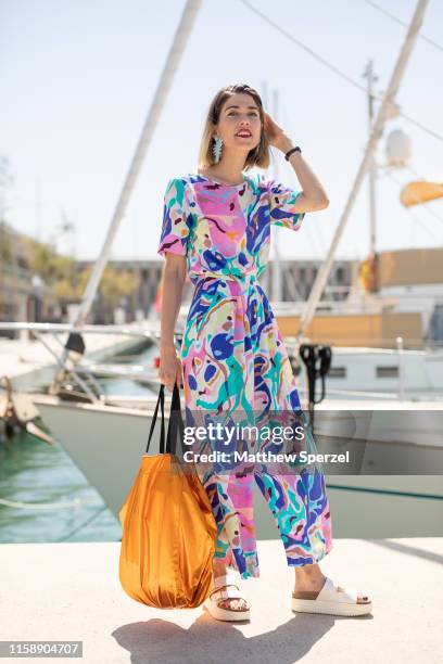 Guest is seen on the street attending 080 Barcelona Fashion Week wearing pastel colorful pattern dress, white sandals, orange tote bag on June 28,...