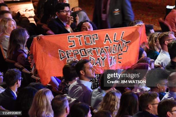 Protester unfurls a banner as Democratic presidential hopefuls participate in the second round of the second Democratic primary debate of the 2020...