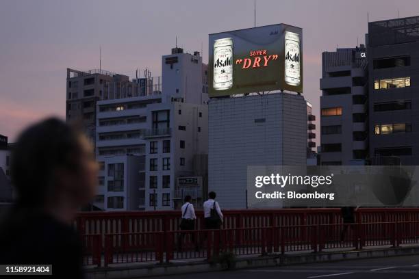 Billboard for Asahi Breweries Ltd.'s Asahi Super Dry beer stands illuminated at dusk in Tokyo, Japan, on Wednesday, July 31, 2019. Japans biggest...