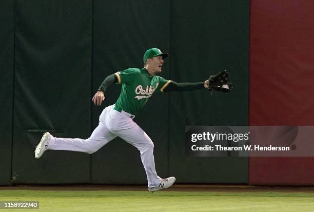 Mark Canha of the Oakland Athletics runs down a fly ball in center field, taking a hit away from Eric Thames of the Milwaukee Brewers in the top of...