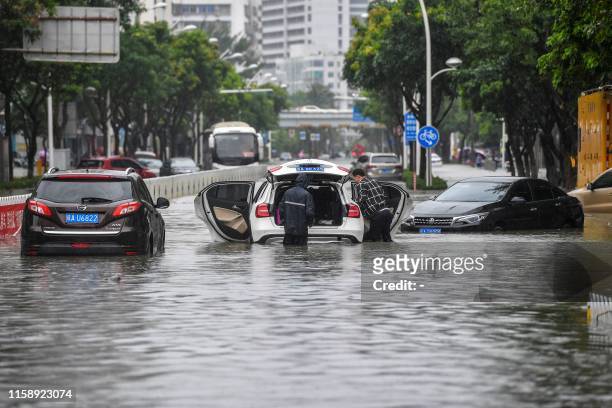 Stranded cars are seen on a flooded street, caused by weather patterns from tropical storm Wipha, in Haikou in southern China's Hainan province on...