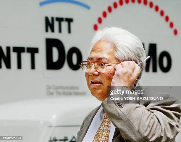 Businessman talks over his mobile phone as he walks in front of a NTT DoCoMo mobile phone shop in Tokyo, 07 August 2003. Japan's top mobile phone...