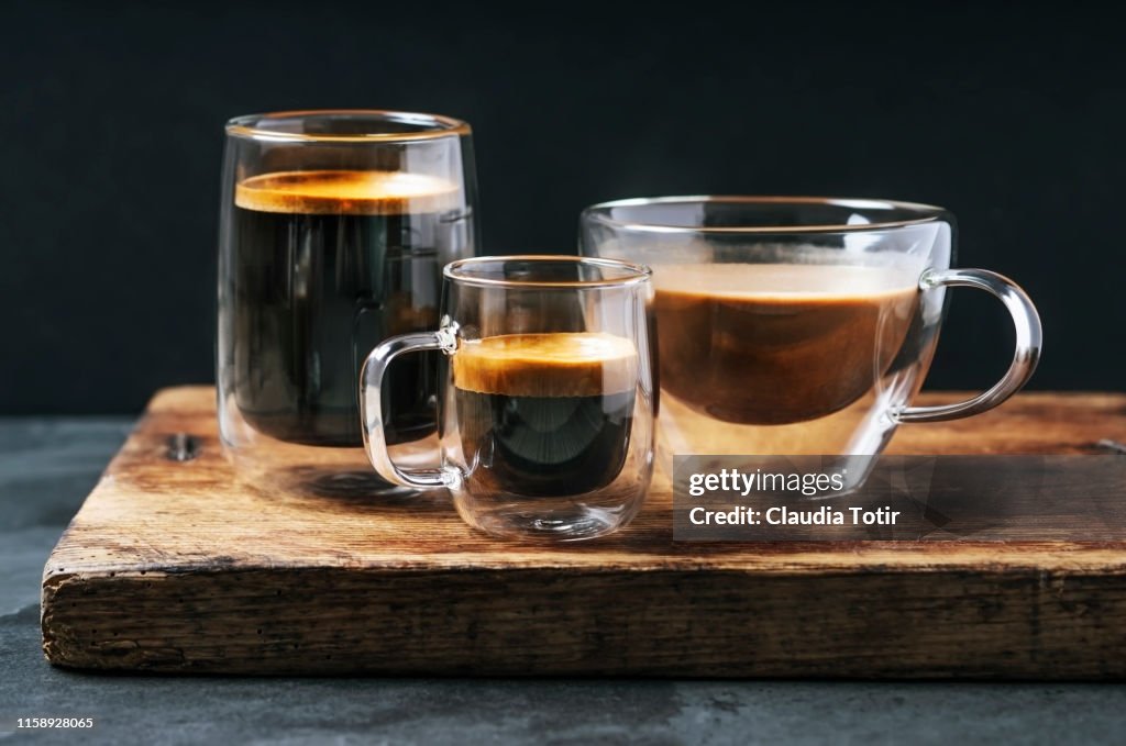 Variety of mugs with coffee and espresso on black background