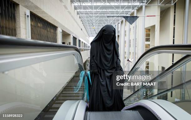 Visitor to the Second Chamber rides an escalator dressed in a niqab, prior to a debate on Islamic face covering in The Hague on November 23, 2016. -...