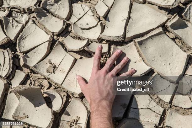 open hand on dry river reservoir climate change mudrack - eroded stock pictures, royalty-free photos & images