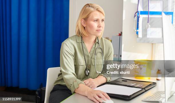female gp checking her medical records - british blonde stock pictures, royalty-free photos & images