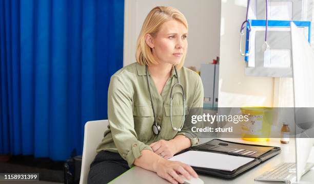 female gp checking her medical records - family doctor stock pictures, royalty-free photos & images