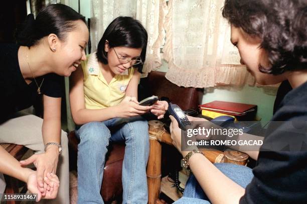 Filipino teenagers check their mobile phones for Y2K bug problems 02 January, 2000. Filipino teenagers are becoming hooked to mobile phone with the...