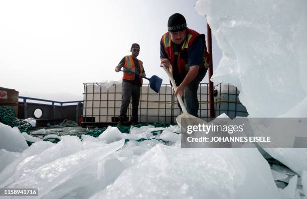 Blair Baker and Taylor Lindsorn shovel pieces of an iceberg in to a container in Bonavista Bay on June 30, 2019 in Newfoundland, Canada. - Iceberg...