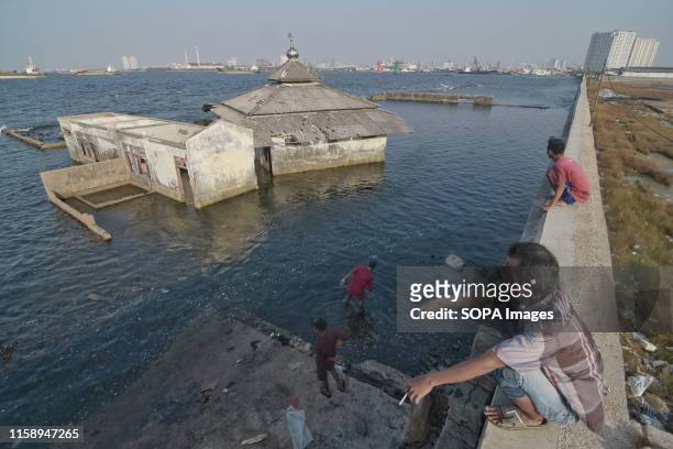 Man squats on the sea wall in the Muara Baru area in Jakarta. To save the low-lying capital of Jakarta from sinking under the sea, Indonesia's...