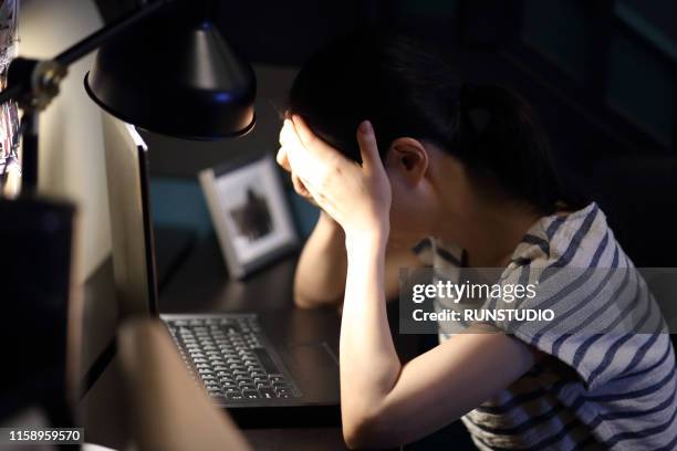 tired woman with head in hand on desk at home - 悩む　女性 ストックフォトと画像