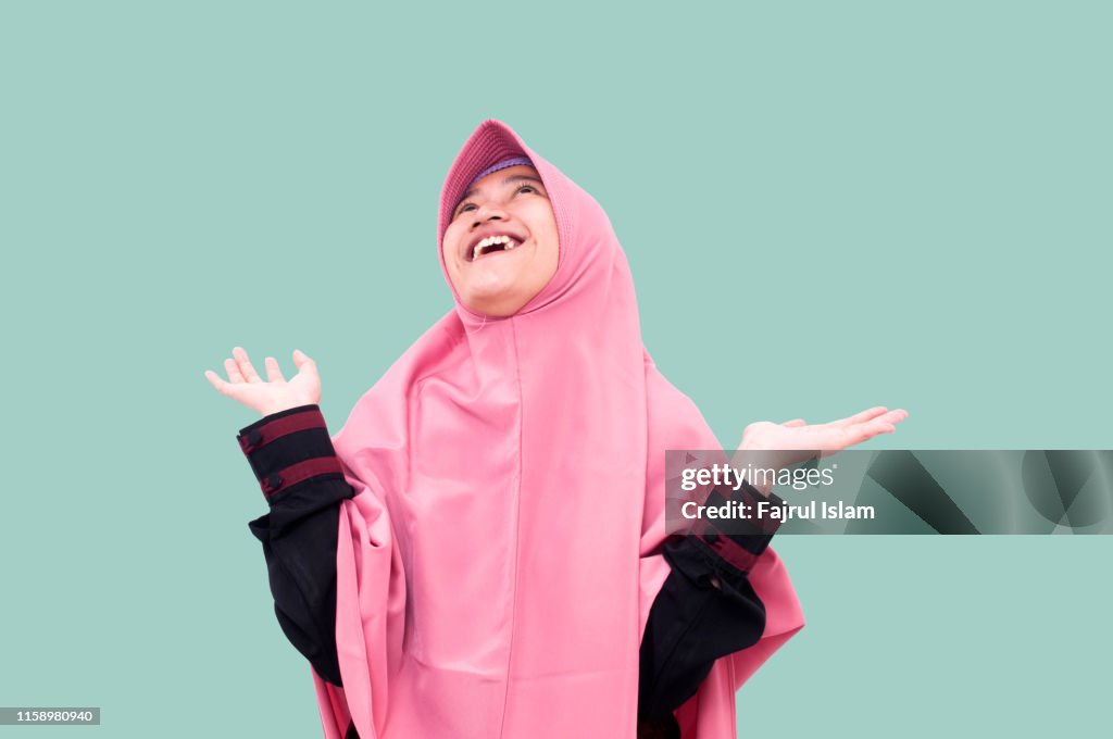 Portrait of young Happy muslim Woman raising her arms in front of Light blue background