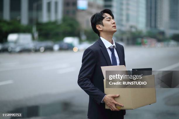 fired businessman carrying box of personal items on street - quitting a job stockfoto's en -beelden