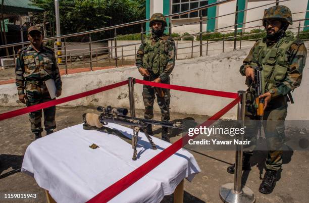 Indian Army troopers stand behind a seized US made sniper rifle recovered by Indian forces at a display during a press conference at Army on August...