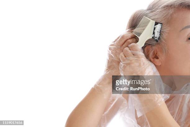 senior woman dyeing her hair - färbemittel stock-fotos und bilder