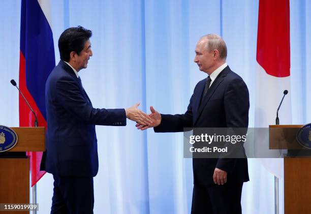 Russian President Vladimir Putin shakes hands with Japanese Prime Minister Shinzo Abe at their news conference at G20 leaders summit on June 29, 2019...