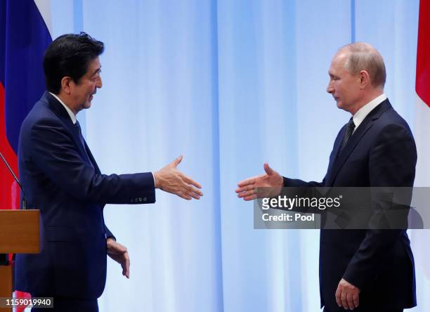 Russian President Vladimir Putin shakes hands with Japanese Prime Minister Shinzo Abe at their news conference at G20 leaders summit on June 29, 2019...