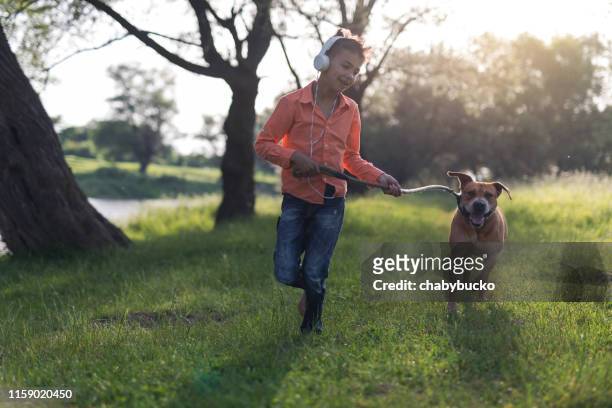 boy running with dog in nature - runaway dog stock pictures, royalty-free photos & images