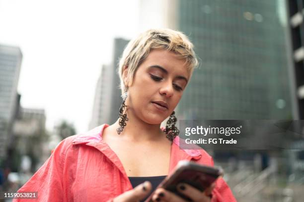 young latin woman using smartphone in the city - teen lesbians stock pictures, royalty-free photos & images