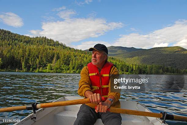 senior man rowing  on tyaughton lake, goldbridge,british columbia,canada. - steering boat stock pictures, royalty-free photos & images