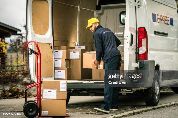 el repartidor carga cajas en un carrito de empuje - van vehicle fotografías e imágenes de stock