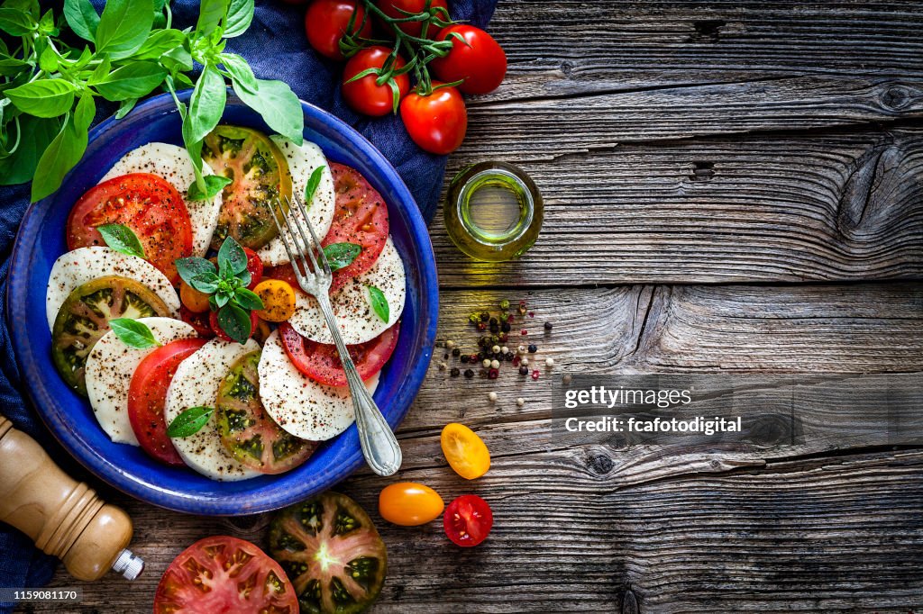Italian food: healthy fresh Caprese salad on rustic wooden table