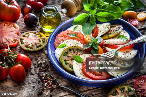 italian food: healthy fresh caprese salad on rustic wooden table - black peppercorn stock pictures, royalty-free photos & images
