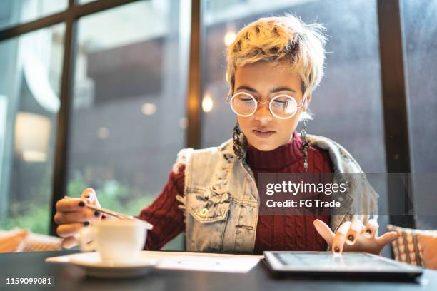 mujer latina revisando algunos gráficos de inversión digital - petite latina fotografías e imágenes de stock