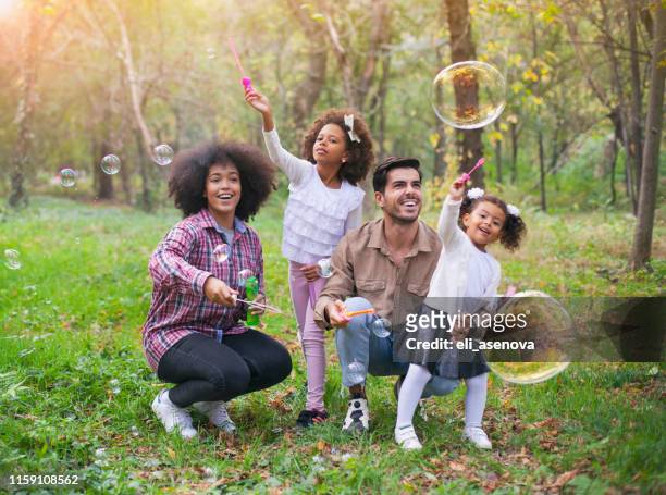 gelukkige familie spelen zeepbellen in het park. - bubbles happy stockfoto's en -beelden