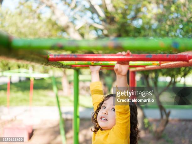 little girl swinging on the monkey bars - monkey bars imagens e fotografias de stock