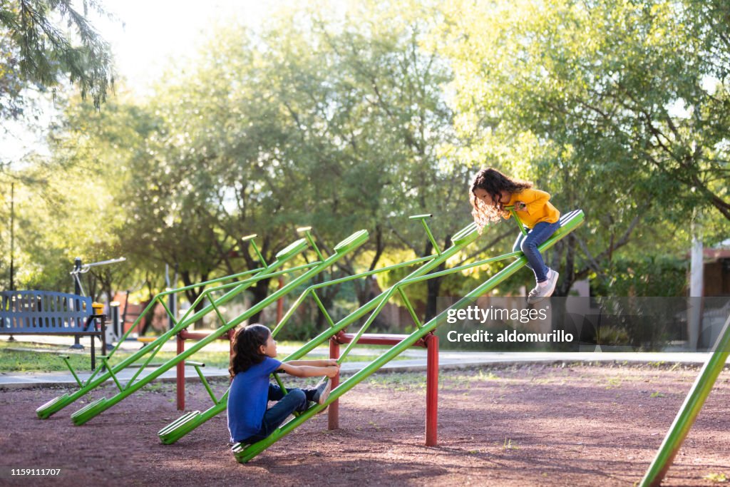 Sisters playing on a seesaw together