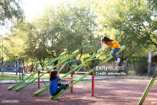 sisters playing on a seesaw together - playground stock pictures, royalty-free photos & images