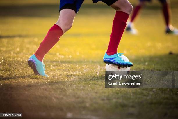 unkenntliche fußballerin, die den ball bei einem spiel anführt. - female feet stock-fotos und bilder