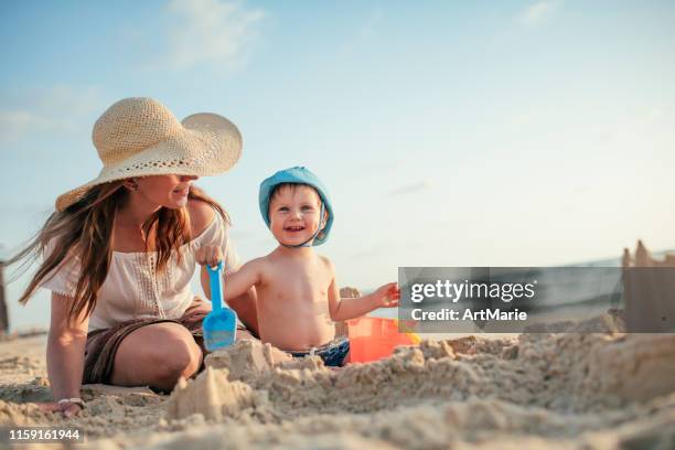 mother and son on the beach playing with sand - sandcastle stock pictures, royalty-free photos & images