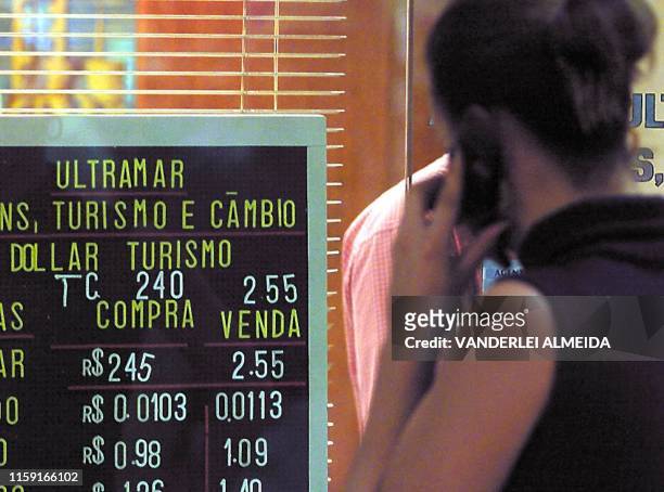 Woman talks on her cell phone while she looks at the exchange rate of the dollar at the financial center in Rio de Janeiro, 11 July 2001. Una mujer...